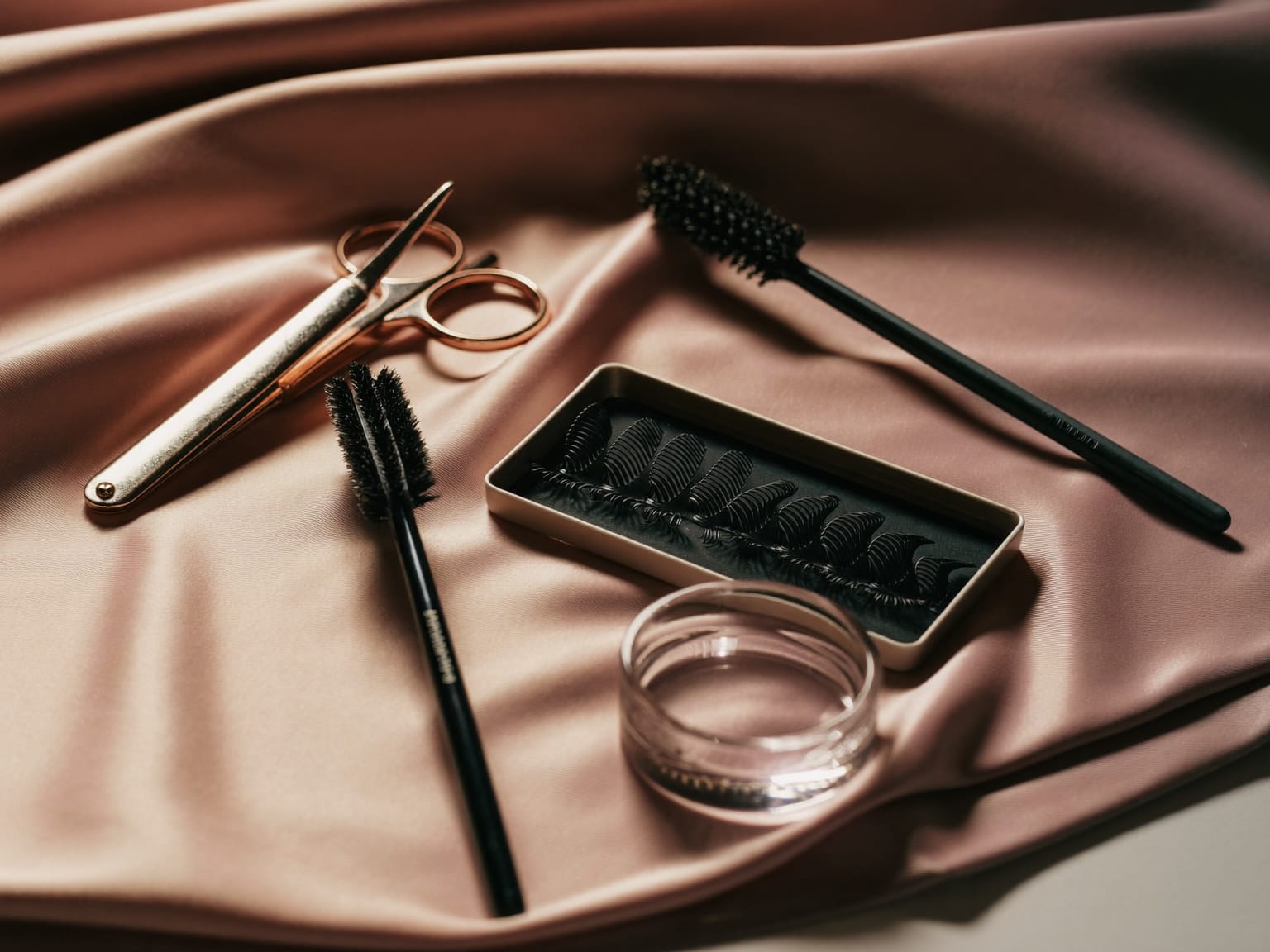 Lash extension tweezers and lash tray on blush satin