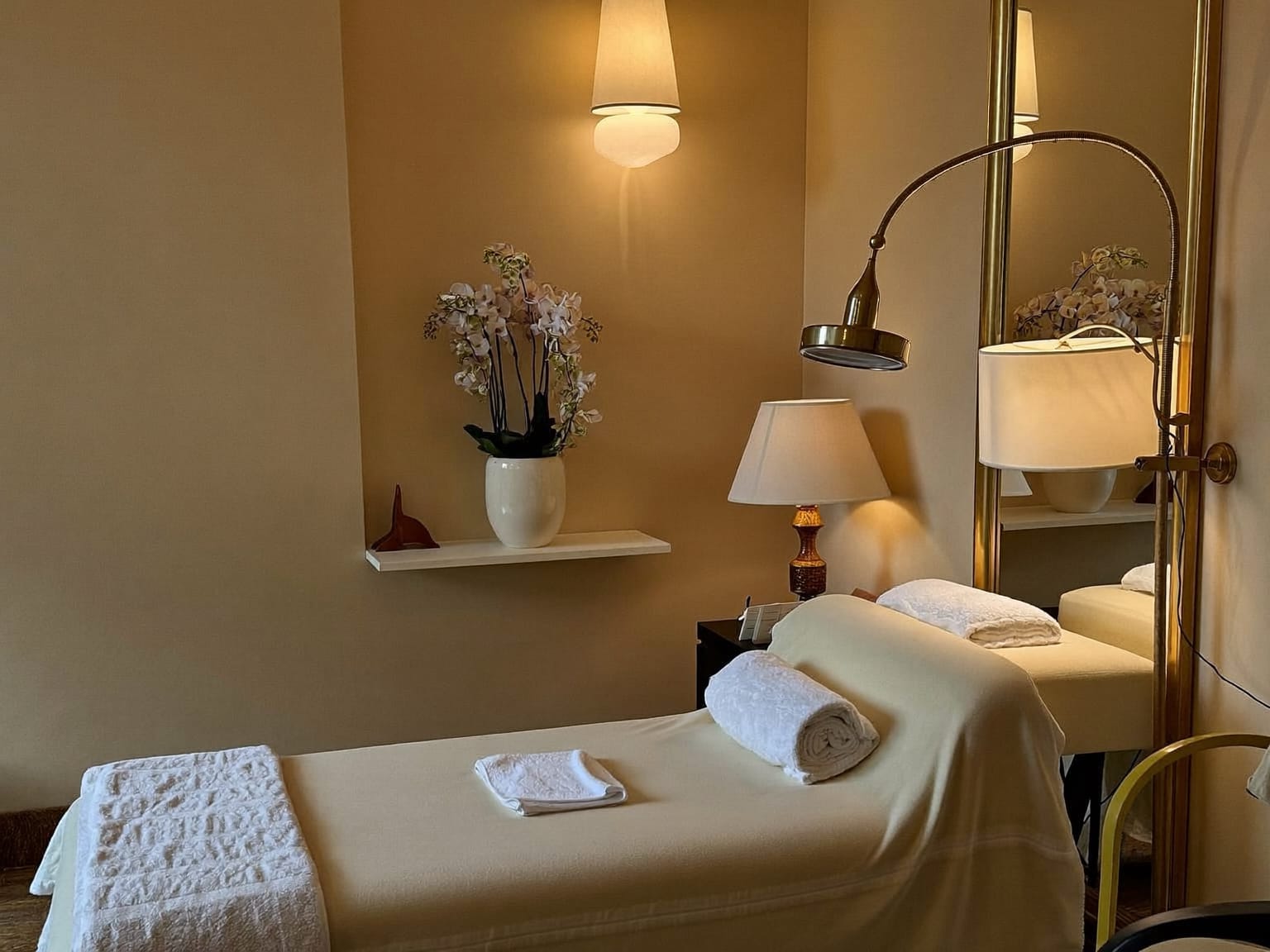 A calm treatment room with a cream bed and warm lamps